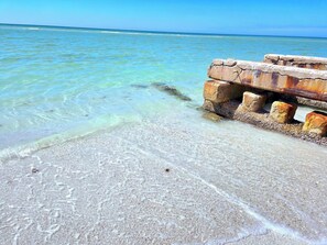 A beach with clear turquoise water and a concrete structure with rusted blocks. - The Village Bungalow of Long Beach in Longboat Key (Longboat Key)