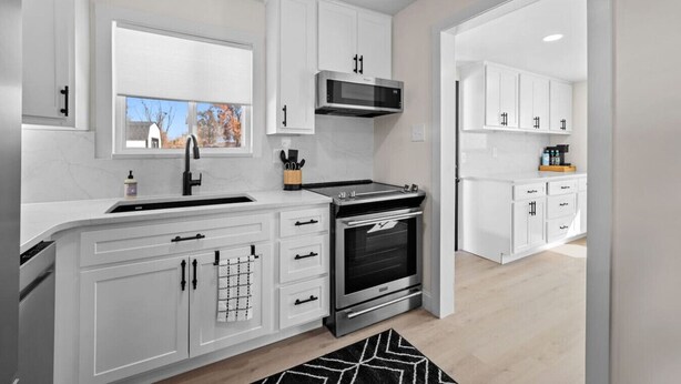 Een moderne keuken met witte kasten, een roestvrijstalen fornuis en een inbouwoven.