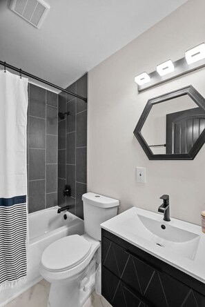 Een moderne badkamer met douche, toilet en wastafel.