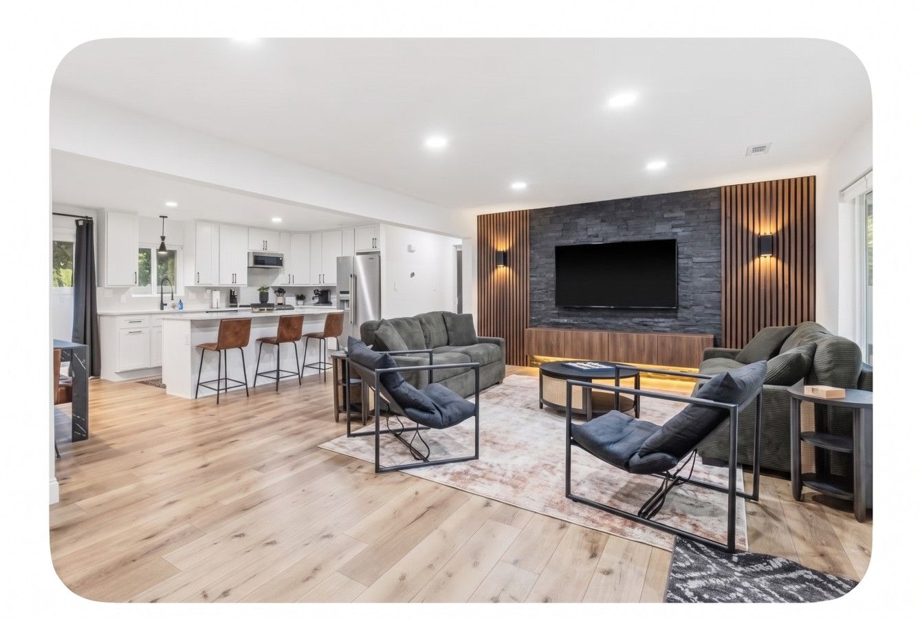Ein modernes Wohnzimmer mit einer Couch, Sesseln und einer TV-Wand.