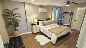 Een slaapkamer met een bed, nachtkastjes, een lamp, een plant, een plafondventilator en een kledingkast.