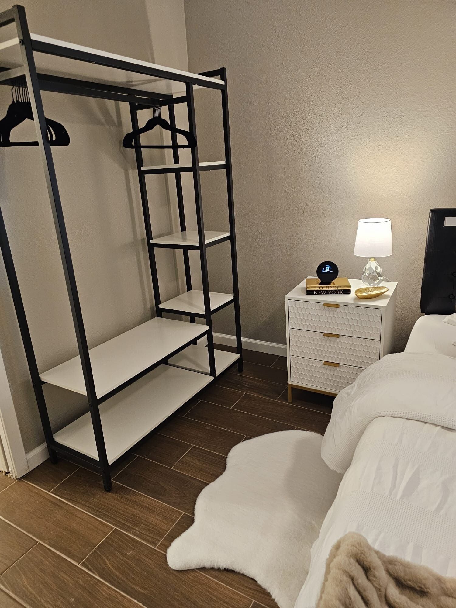 A bedroom with a bunk bed, a bedside table with a lamp, and a white dresser.