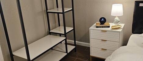 A bedroom with a bunk bed, a bedside table with a lamp, and a white dresser.
