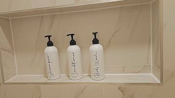 Three white bottles with black pumps on a beige tiled shelf.