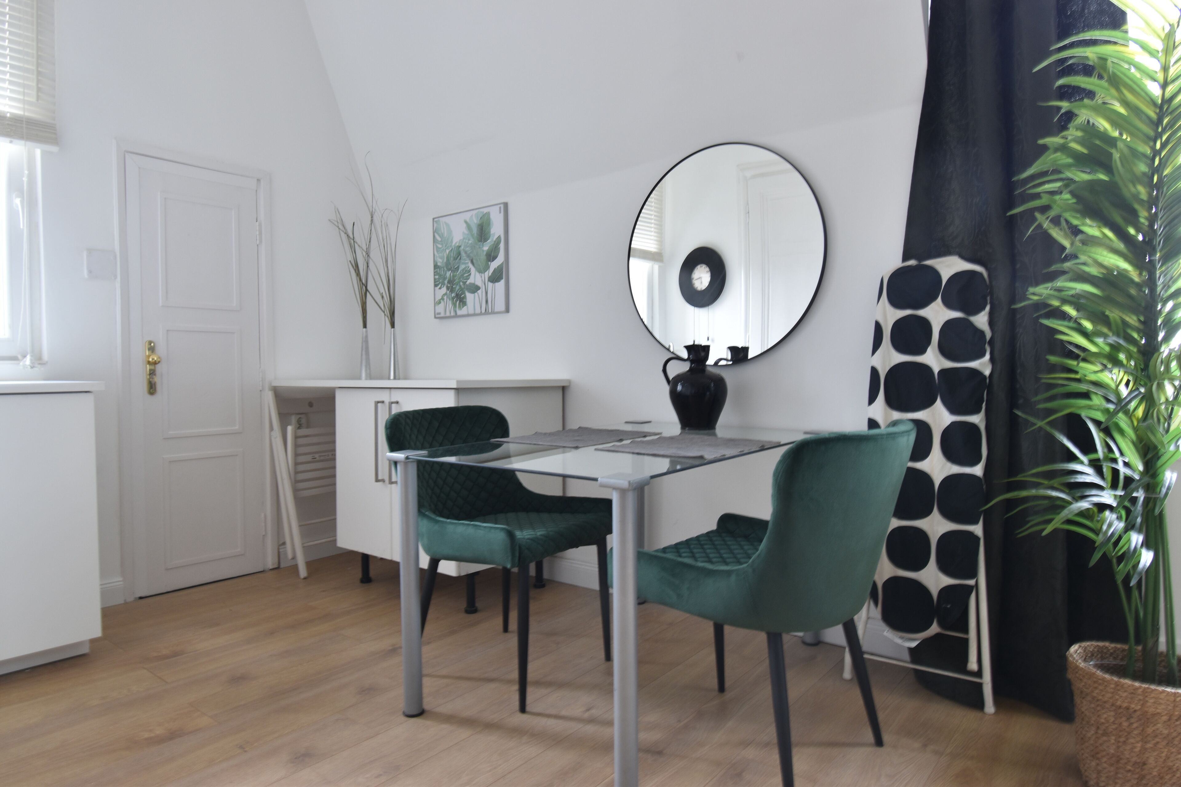 A modern kitchen with a dining table, chairs, and a large mirror.
