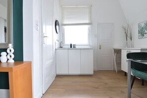 A modern kitchen with white cabinets, a wooden countertop, and a window with blinds.