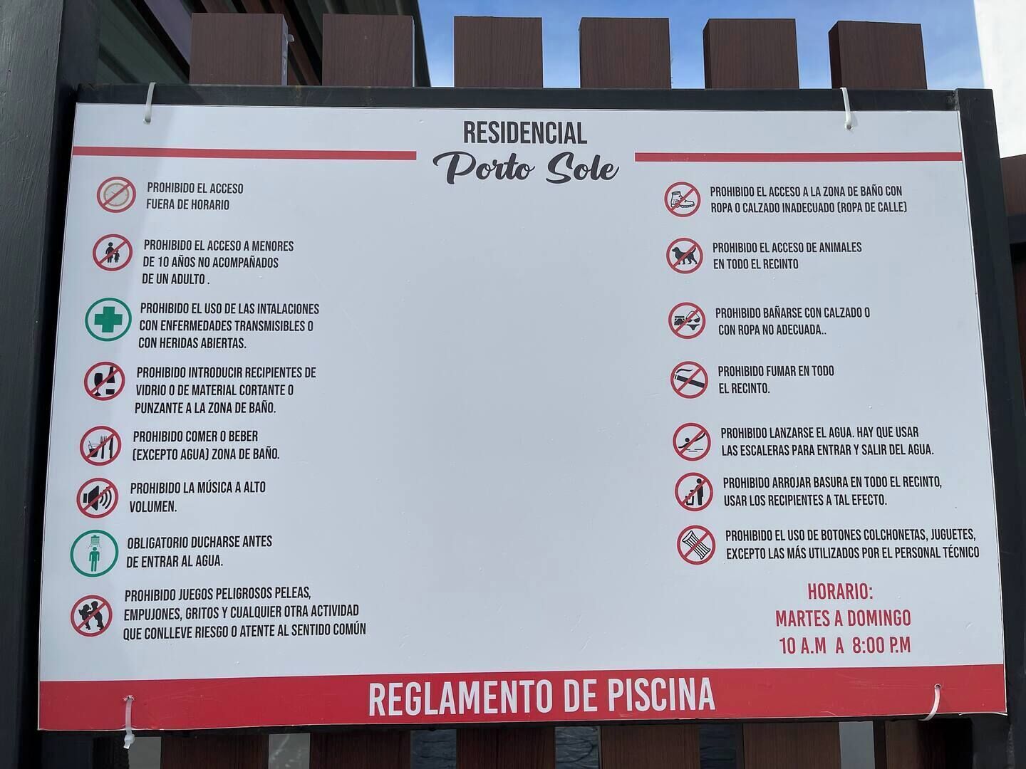 A sign listing rules for a residential pool area, including prohibitions on outside access, swimming with inadequate clothing, and bringing pets.