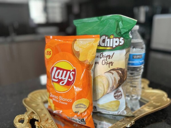 Una bolsa de papas Lays sabor queso blanco y una bolsa de papas con etiqueta verde, sobre una bandeja.