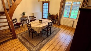 Uma sala de jantar com mesa redonda, cadeiras, um lustre e uma escada.