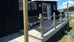 A wooden deck with a bench, a covered area with a sign, and a rope barrier.
