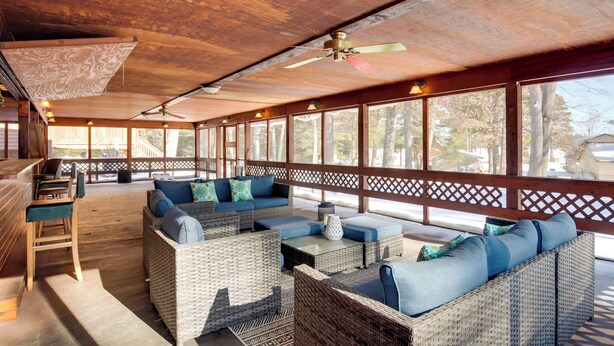 A covered outdoor seating area with wicker furniture and a wooden ceiling. - Snowmobile & Enjoy Eagle River! ‘Southside Lodge’ (Eagle River)