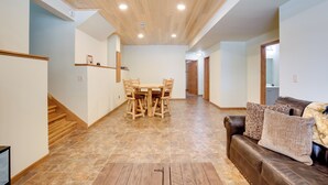 Amplia sala de estar con piso de madera, una mesa de comedor con sillas, un sofá de cuero marrón y una escalera que conduce a otro nivel.