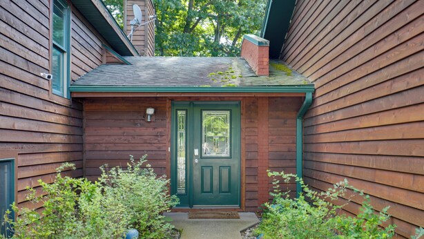 Una casa de madera con una puerta verde y un porche pequeño.