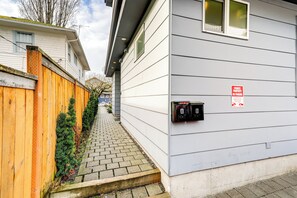 A narrow pathway leading to a house with a wooden fence on one side and a mailbox on the other.