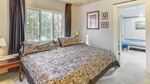 Ein Schlafzimmer mit einem großen Bett, einem Schreibtisch und einem Fenster mit Vorhängen.