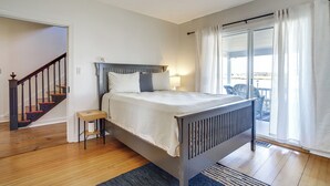 A bedroom with a wooden bed, a small bedside table, a nightstand, a window with curtains, and a view of the outdoors. - Riverfront Gem w/ Fire Pit in Eden (Eden)