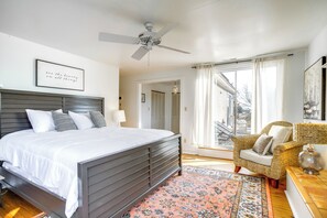 A bedroom with a bed, a ceiling fan, a wicker chair, and a view of the outside. - Riverfront Gem w/ Fire Pit in Eden (Eden)