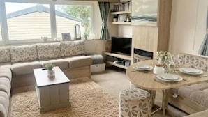 Una sala de estar acogedora con sofá, televisor y mesa de comedor.