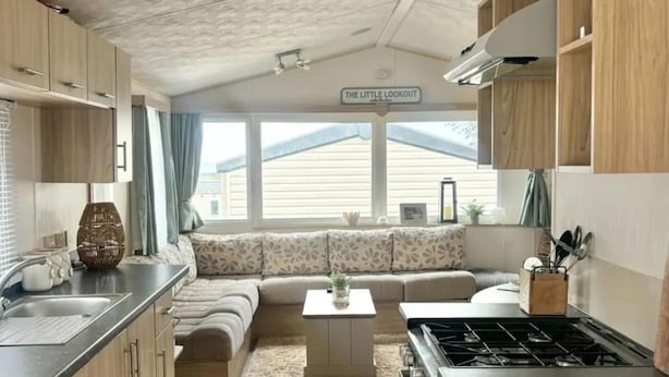 Una cocina compacta con estufa a gas, armarios de madera y un pequeño comedor.