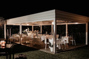 A covered outdoor dining area with tables and chairs, surrounded by a white structure.