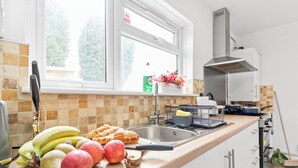 A kitchen with a window, a sink, and various fruits and vegetables on the counter.