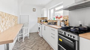 A modern kitchen with white cabinets, a wooden countertop, a built-in oven, and a stove.