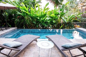 A swimming pool with two lounge chairs and a table in the foreground, surrounded by lush greenery. - Kitchen, Saltwater Pool, Fast Wifi, Queen Bed, Air Conditioning - "Mar" (San Francisco)