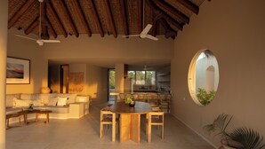 Un vaste espace de vie comprenant une table ronde en bois, un canapé et un ventilateur de plafond.