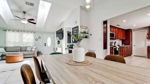 A spacious living area with a dining table, sofa, and kitchen in the background.