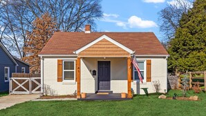 A single-story house with a front porch, a chimney, and a small front yard.