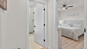 Een slaapkamer met een bed, een plafondventilator en een bord aan de muur.