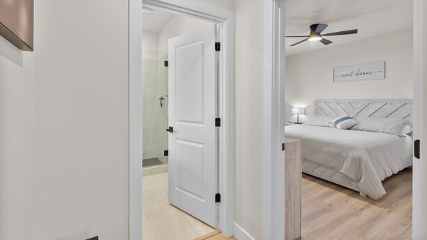 Quarto com cama, ventilador de teto e placa na parede.