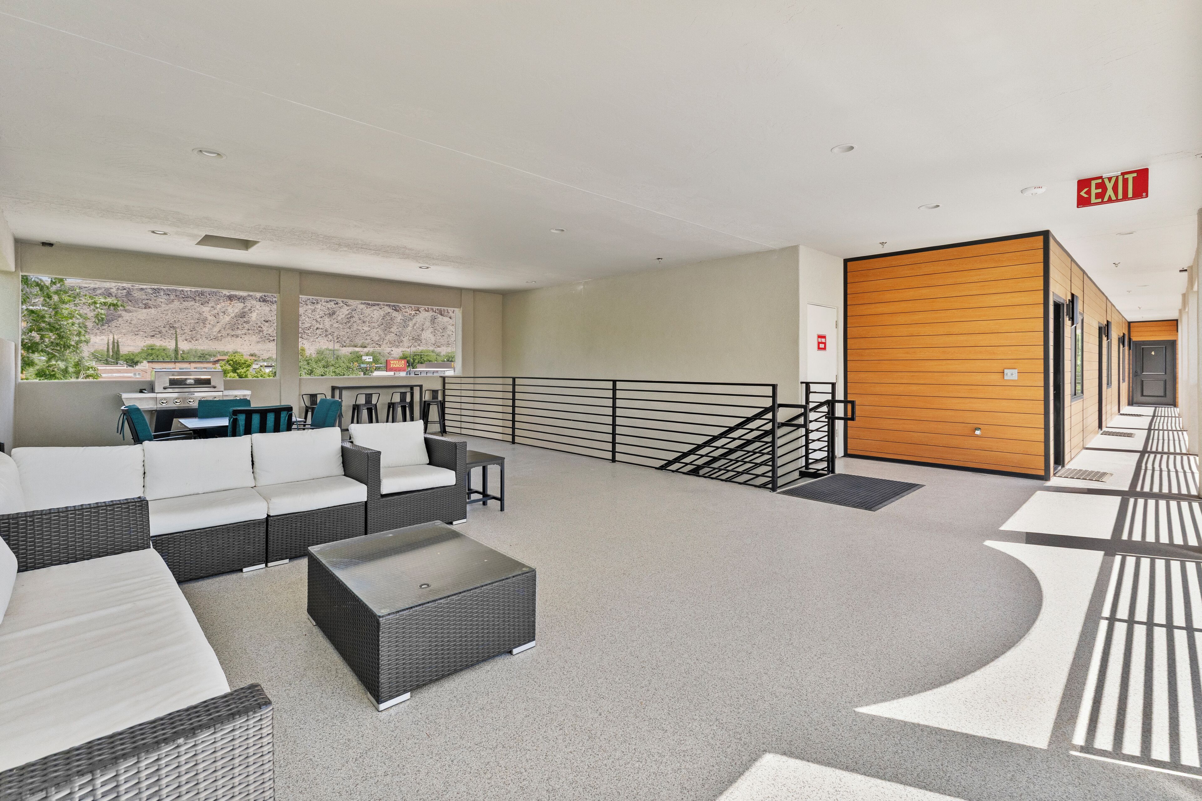 A modern lobby with a seating area, a staircase, and an exit sign.