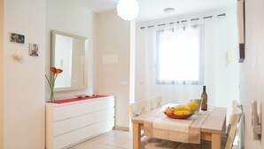 Una cocina moderna con armarios blancos, encimera roja y un comedor con mesa y sillas de madera.
