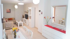 Una sala moderna con sofá, mesa de comedor y armarios blancos.