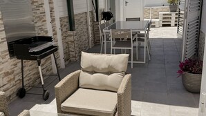 An outdoor patio with wicker furniture, a grill, and a view of the city. - Pambnb - House next to the Beach, Terrace, Fiber Wi-Fi, BBQ (Abades)