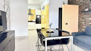 A modern living room with a dining area, a sofa, a TV, and a kitchen in the background. - Pambnb - House next to the Beach, Terrace, Fiber Wi-Fi, BBQ (Abades)