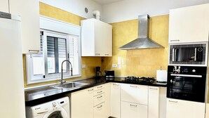 A compact kitchen with a washing machine, a stove, and a microwave. - Pambnb - House next to the Beach, Terrace, Fiber Wi-Fi, BBQ (Abades)