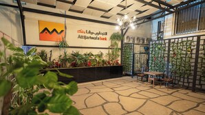 A reception area with a check-in counter, a wall-mounted sign, and a seating area with a table and chairs. - lotus Altahrir hotel (Cairo)