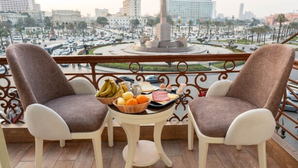 A balcony with two chairs and a table with fruits and eggs. - lotus Altahrir hotel (Cairo)