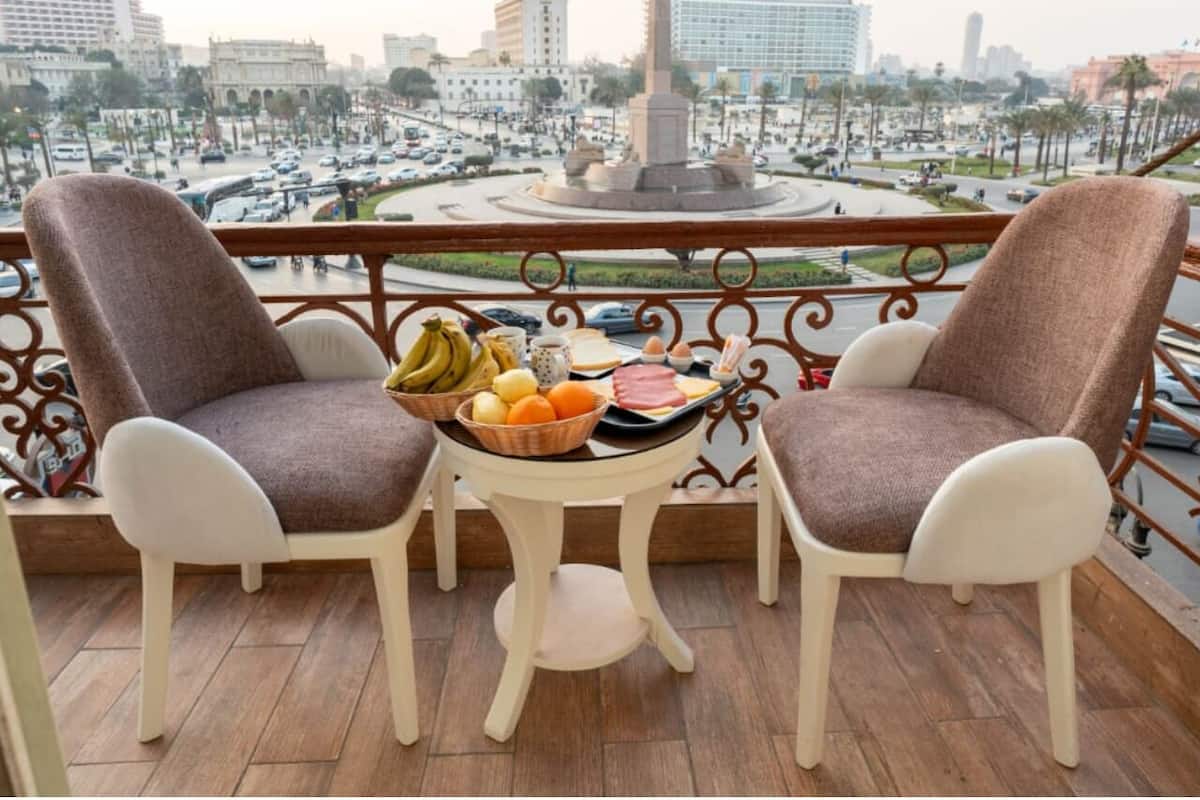 Un balcón con dos sillas y una mesa con frutas y huevos.