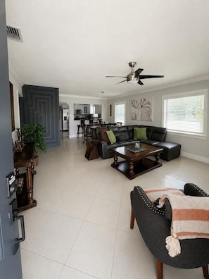 A modern living room with a sectional sofa, a coffee table, and a dining area in the background.