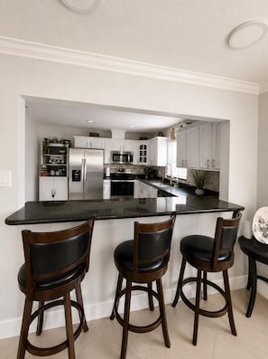 A kitchen with a central island, bar stools, and a refrigerator.