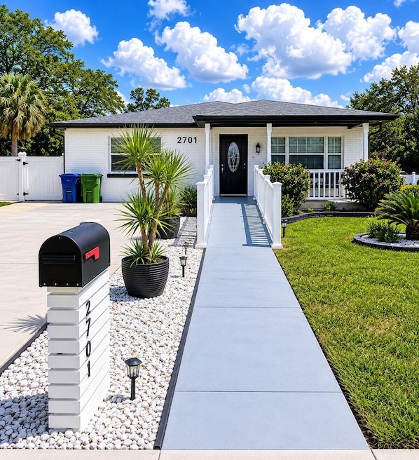 A single-story house with a front porch, a mailbox, and a driveway leading to the entrance.