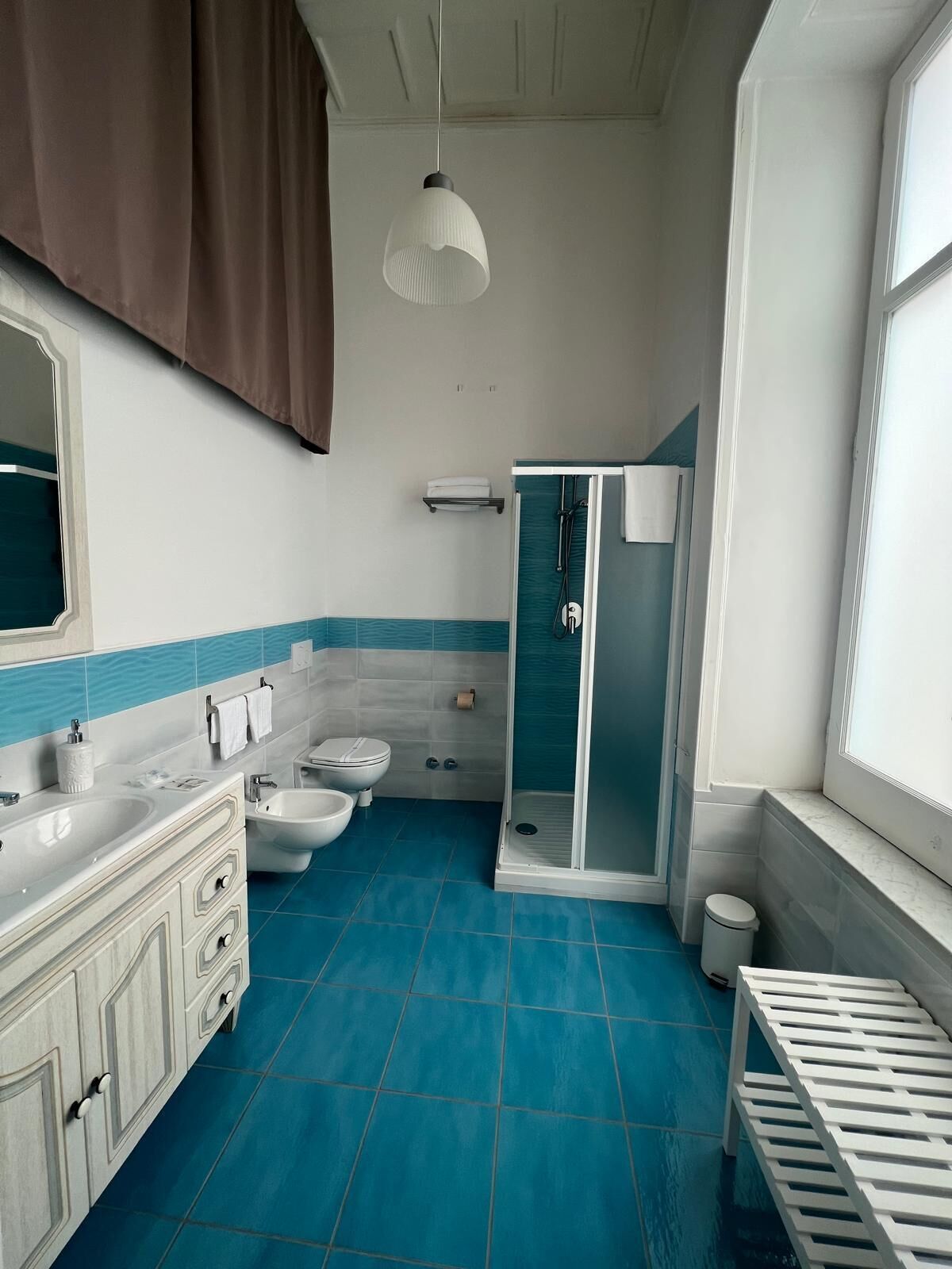 A bathroom with a shower, toilet, bidet, and sink.