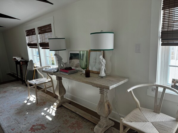 A dining area with a wooden table, two chairs, a lamp, and a window with blinds.