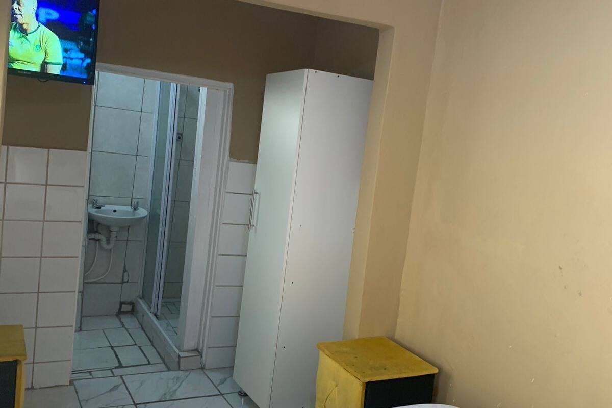 Hotellihuone, jossa on sänky, televisio, vaatekaappi, pesuallas ja suihku.