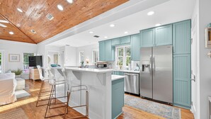 Une cuisine moderne avec des armoires de couleur turquoise, des appareils en acier inoxydable et un plafond en bois.