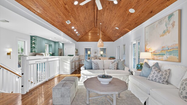 Un salon spacieux avec un plafond en bois, des meubles blancs et un grand tableau accroché au mur.