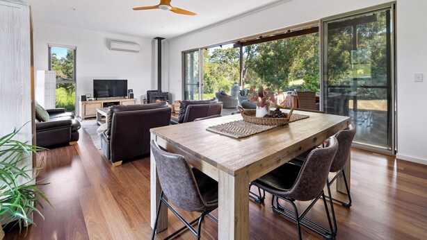 Una sala de estar moderna con una mesa de comedor de madera, sofás de cuero y un amplio ventanal con vistas al exterior.